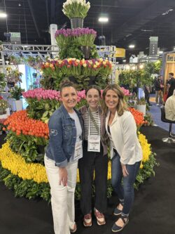 Three girls standing in front of a tower of tulips at the TPIE conference in Florida.